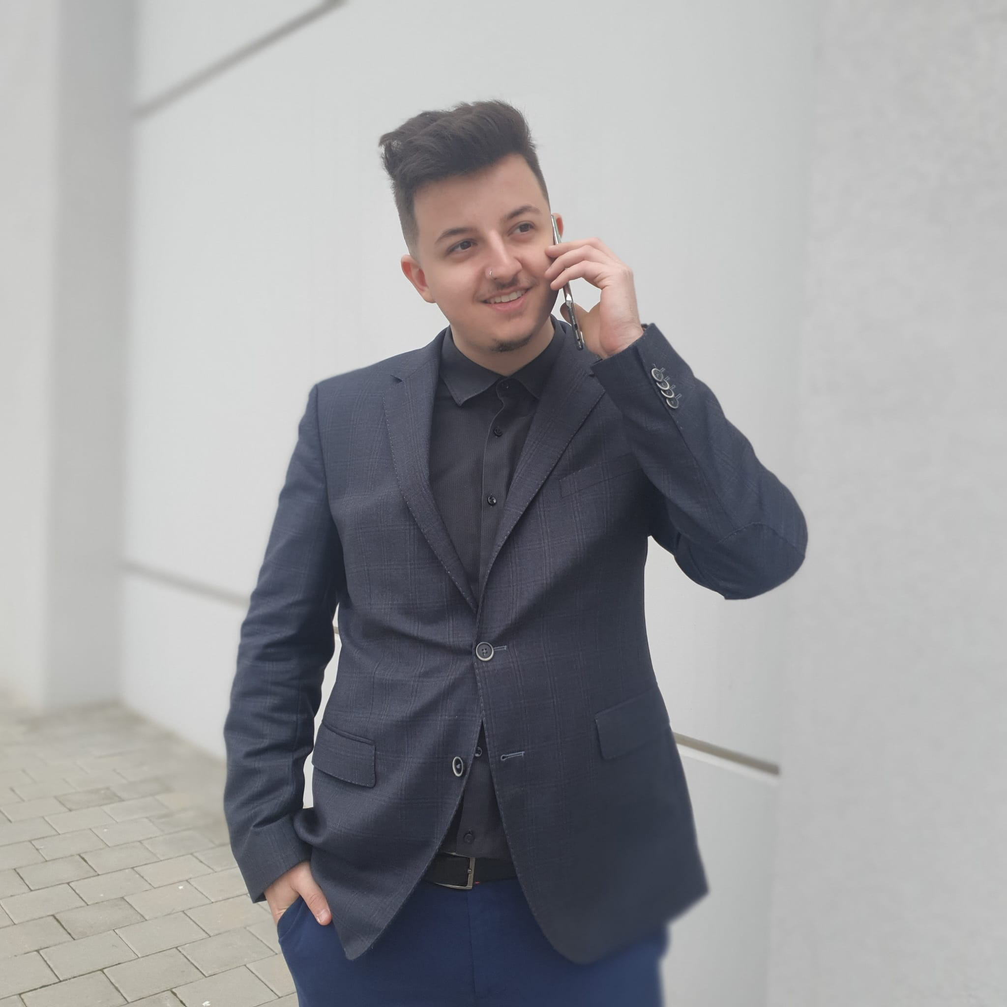 Picture of the owner of the website, Ronaldo George, in a suit, holding a phone to his ear, smiling.